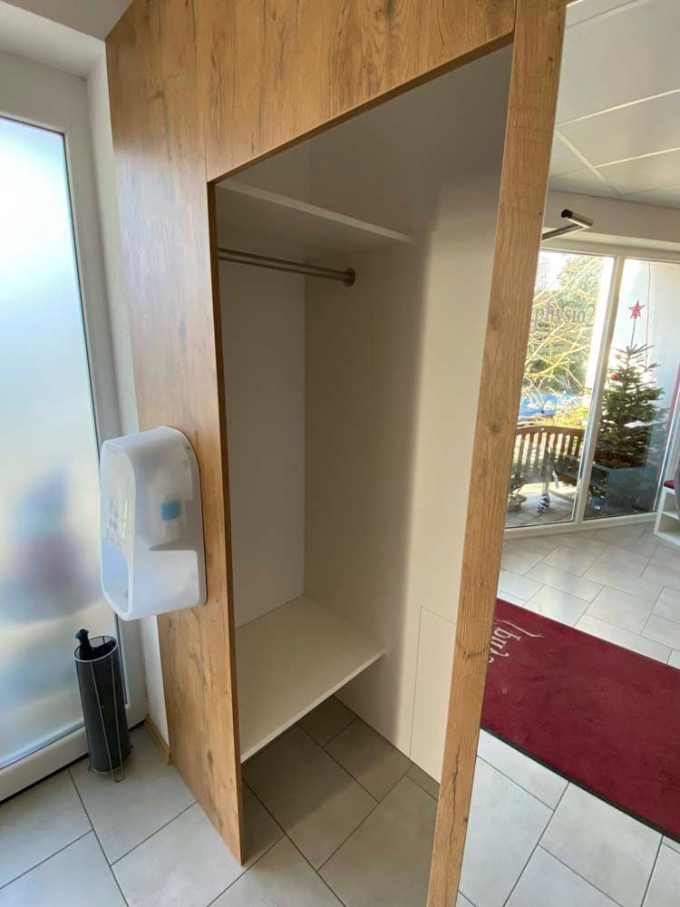 Ein Schrank mit einem Regal und einem Spender für Händedesinfektionsmittel in einem Flur.