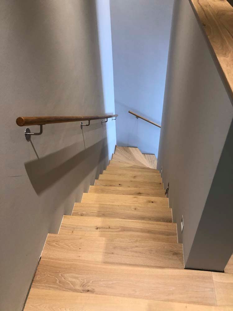 Eine Holztreppe mit Holzhandlauf, die in den zweiten Stock führt.