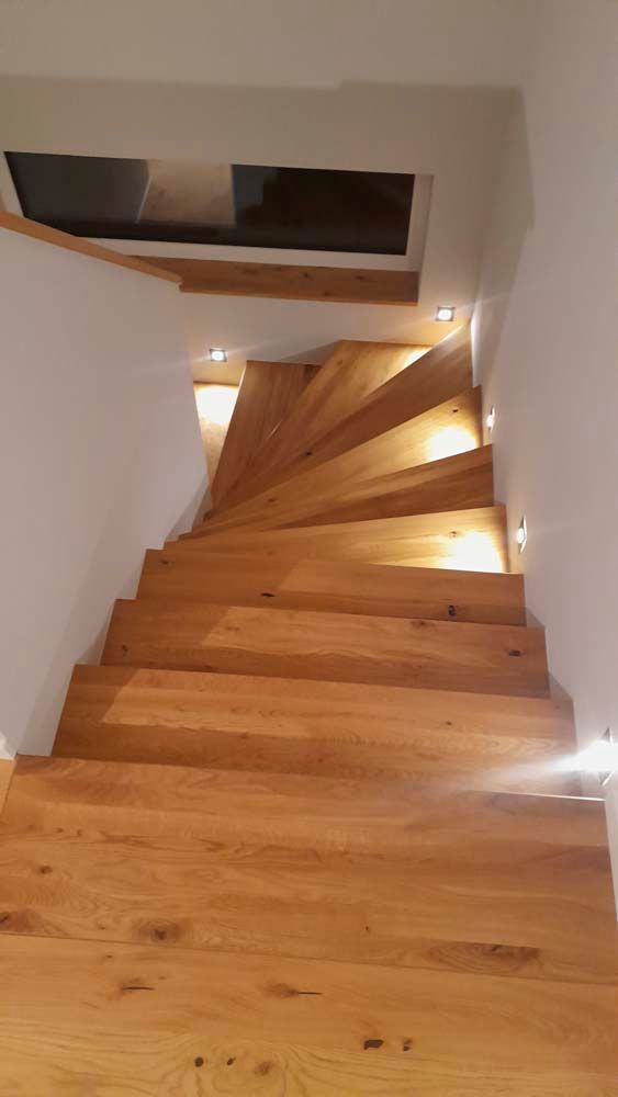 Eine hölzerne Wendeltreppe, die in den zweiten Stock eines Hauses führt.