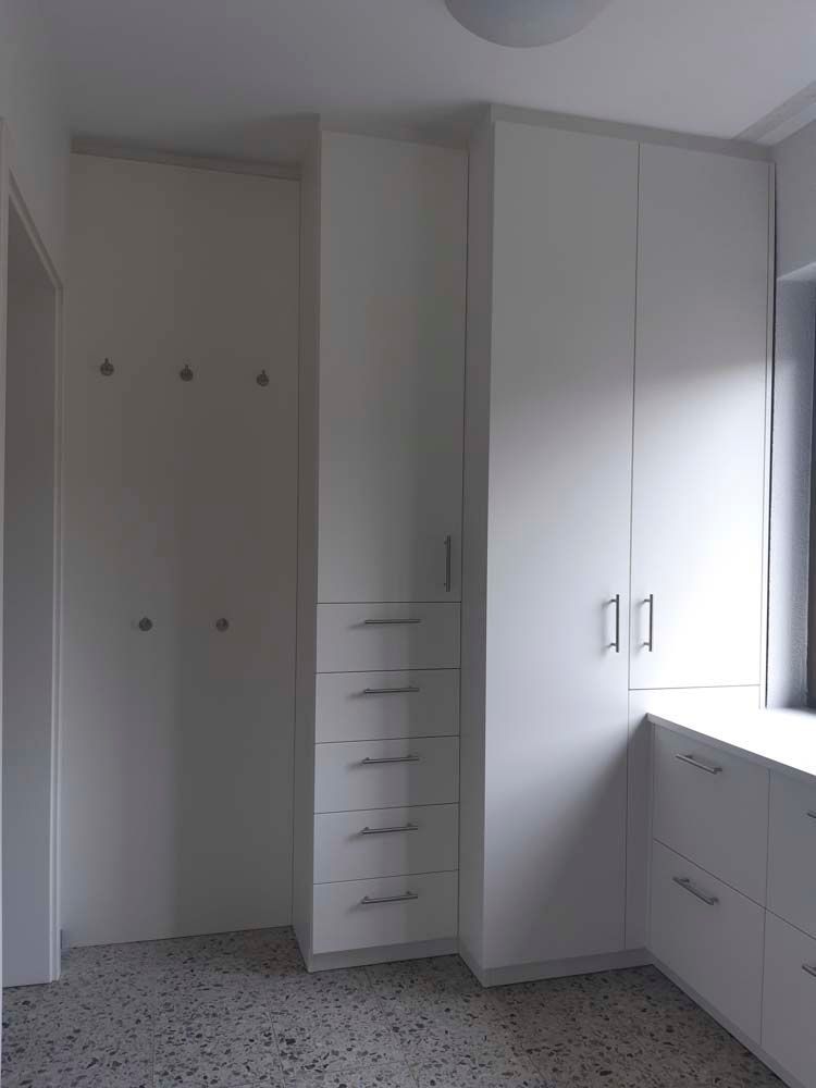 Ein Zimmer mit weißen Schränken und Schubladen und einem Fenster