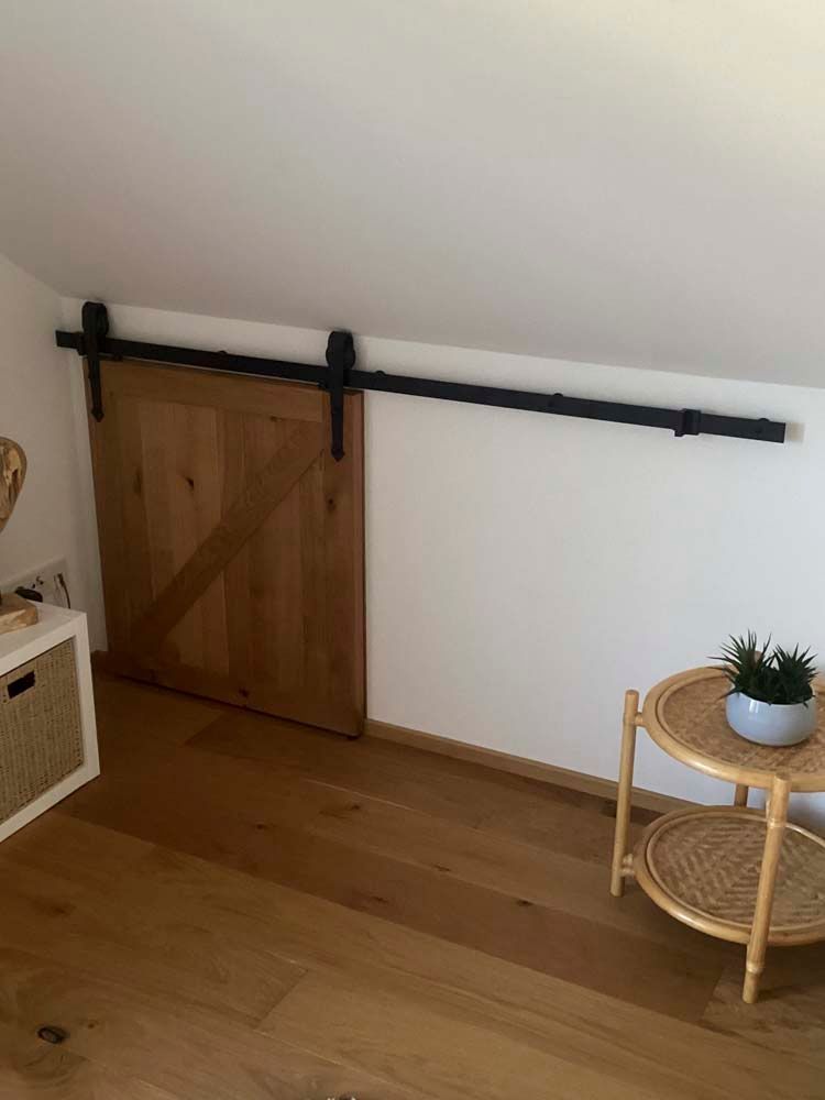 In der Ecke des Zimmers befindet sich eine Schiebetür im Scheunenstil.