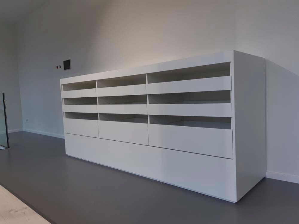 Eine weiße Kommode mit Schubladen und Regalen in einem Zimmer.