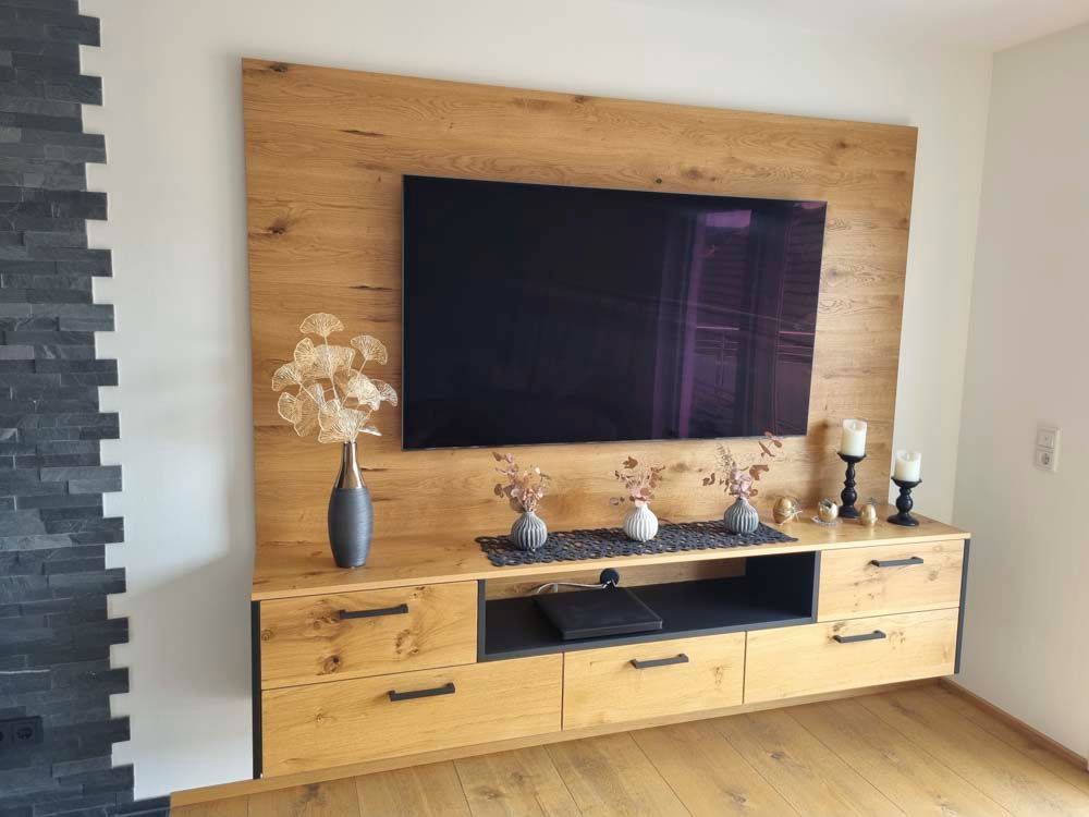 Ein Wohnzimmer mit einem Entertainment-Center aus Holz und einem Flachbildfernseher an der Wand.
