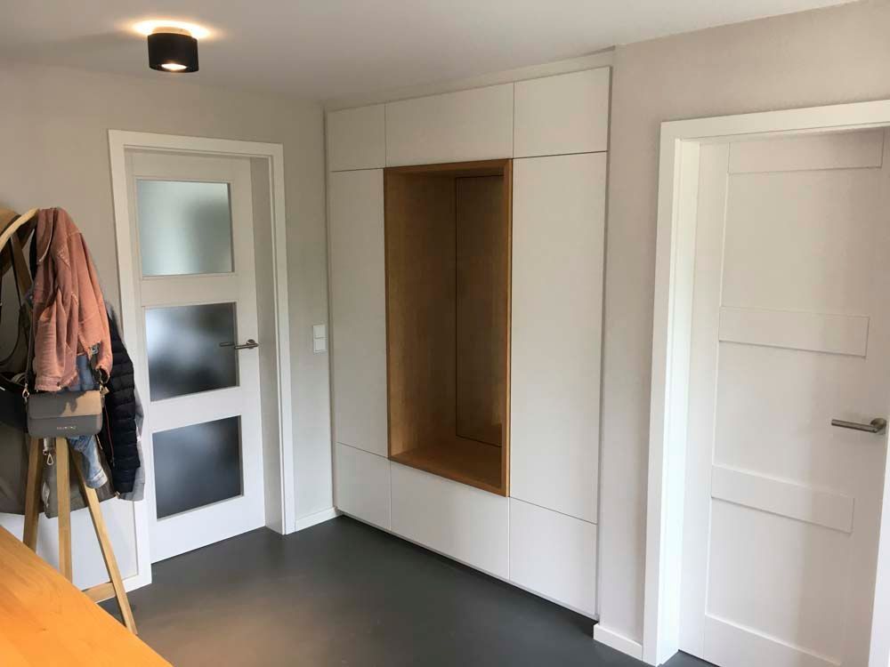 Ein Flur mit weißen Schränken und einer Garderobe.
