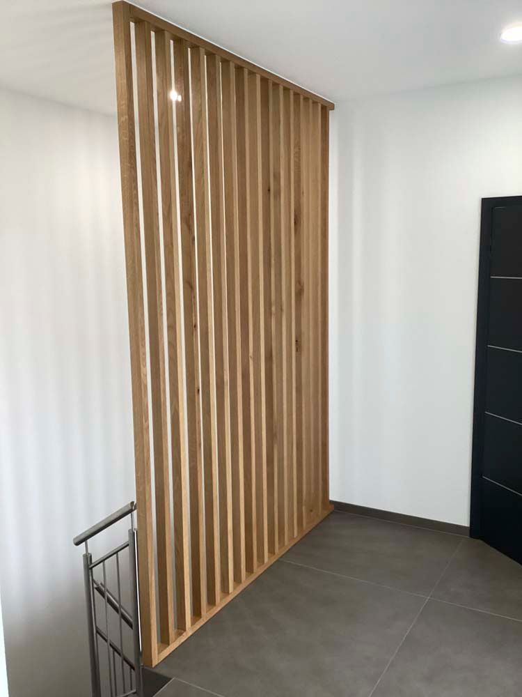 Ein hölzerner Raumteiler in einem Flur neben einer Treppe.