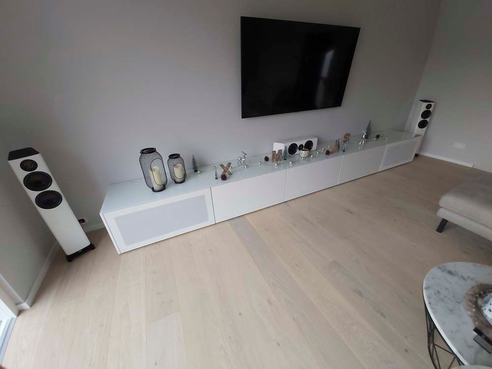 Ein Wohnzimmer mit einem langen weißen Entertainment-Center und einem Flachbildfernseher.