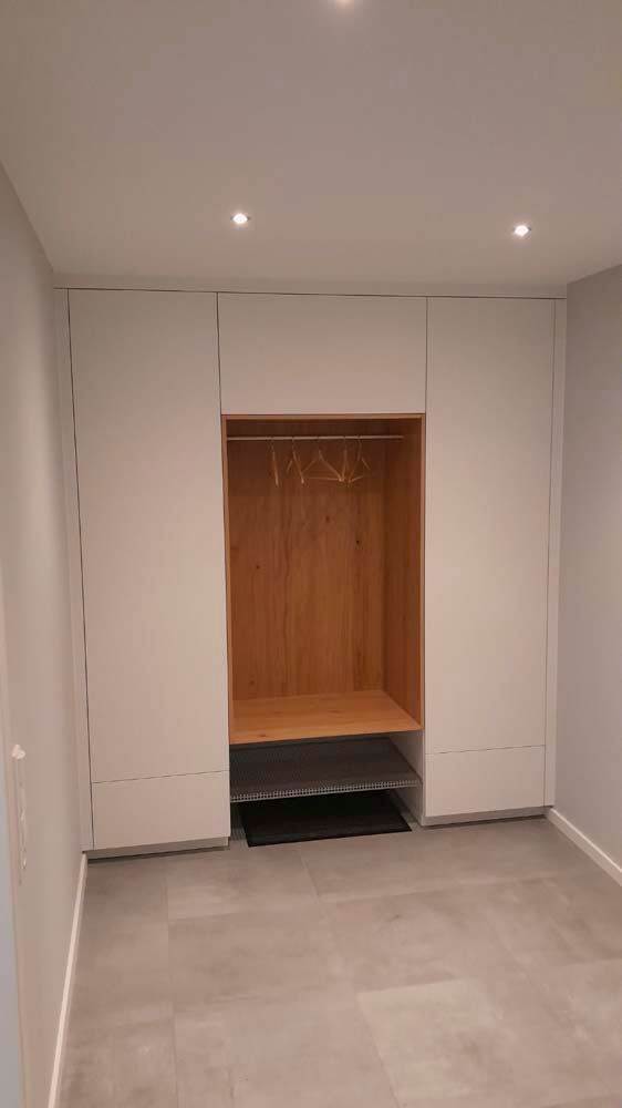 Ein Flur mit weißen Schränken und einer Holzbank.