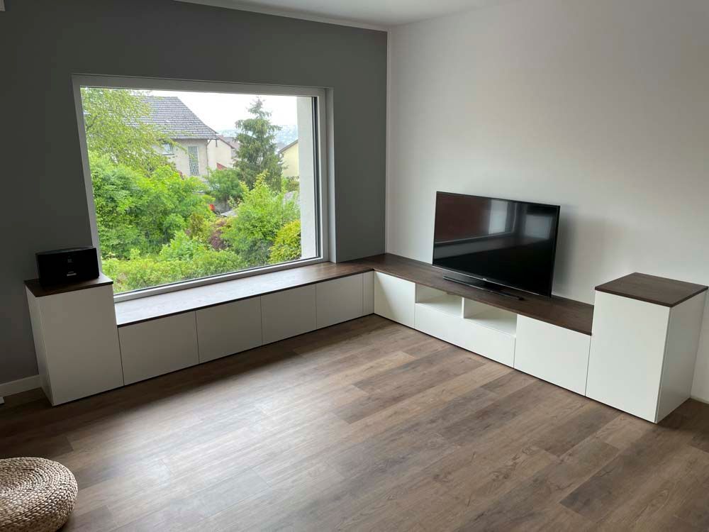 Ein Wohnzimmer mit großem Fenster und Flachbildfernseher.