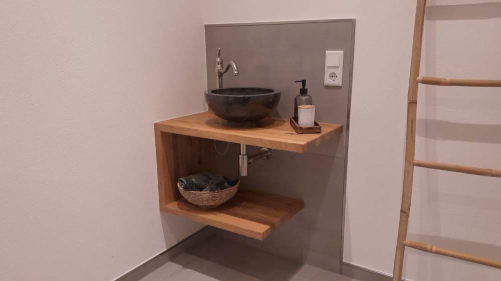 Ein Badezimmer mit einem Waschbecken auf einem Holzregal.