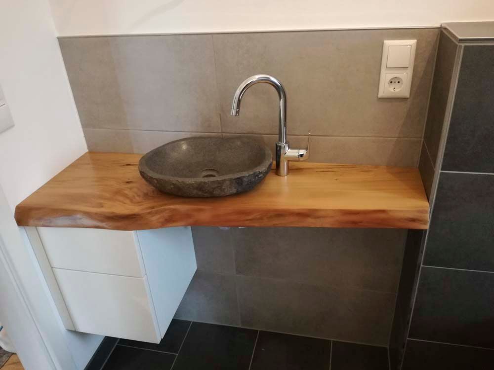 Auf einer Holztheke steht ein Waschbecken.