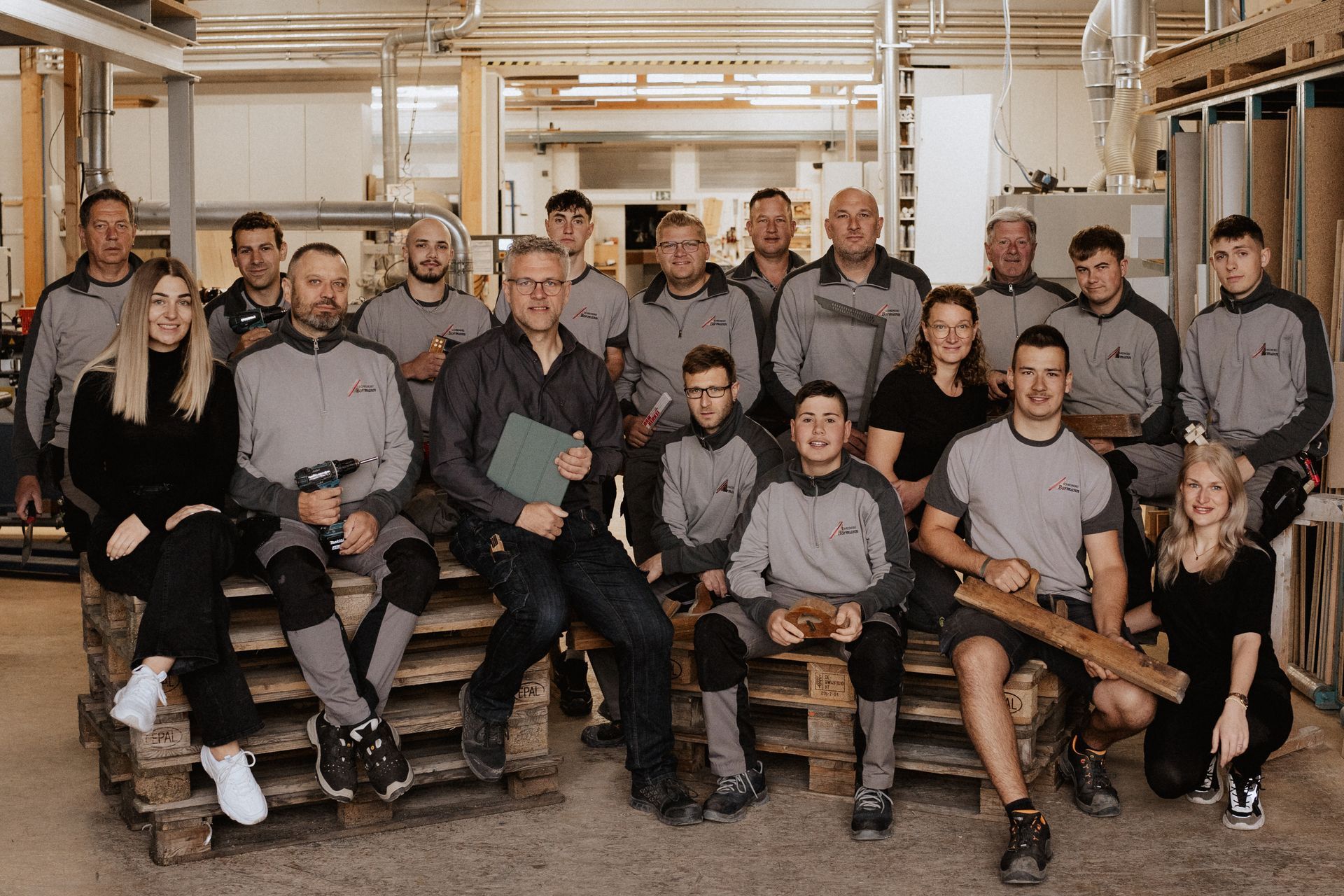 Eine Gruppe von Menschen posiert in einer Fabrik für ein Foto.