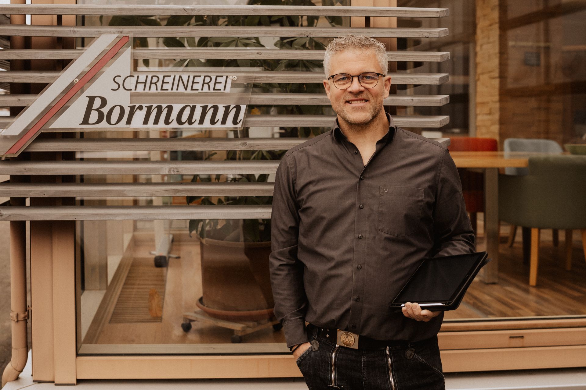 Ein Mann steht mit einem Tablet vor einem Geschäft.