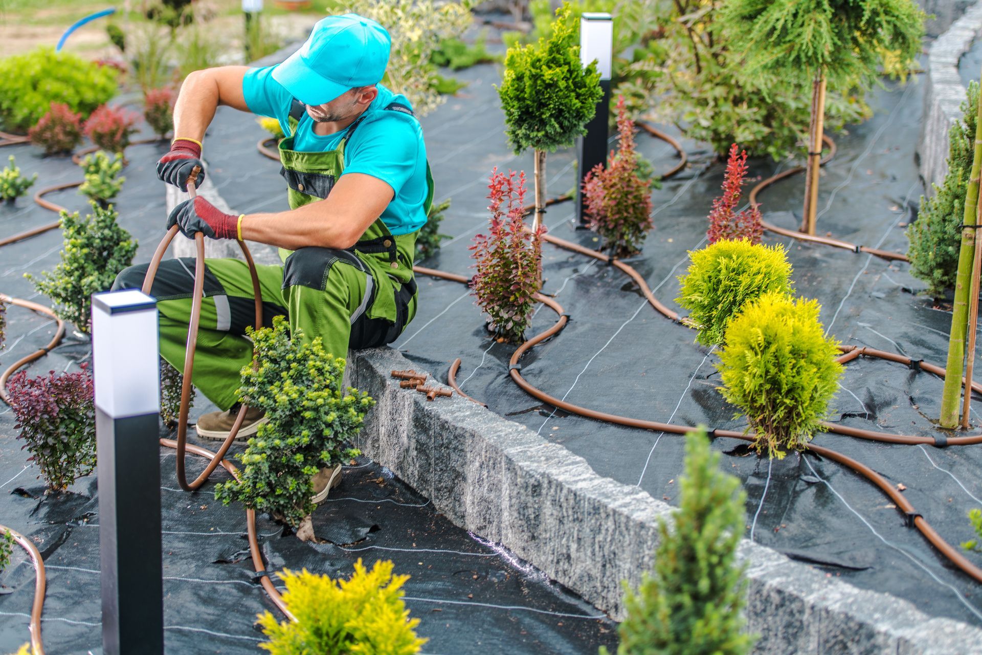 Un jardinier installe un système d'irrigation dans un jardin en raccordant les tuyaux.