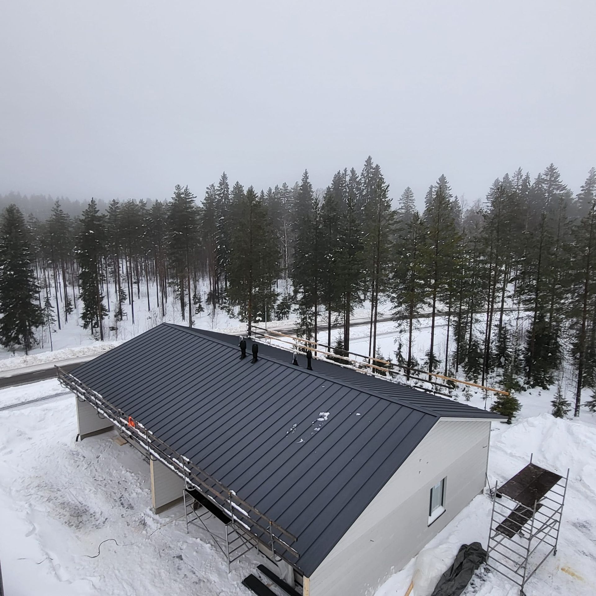 Uuden katon asennus ja kattoturvatuotteiden viimeistely talvimaisemassa.