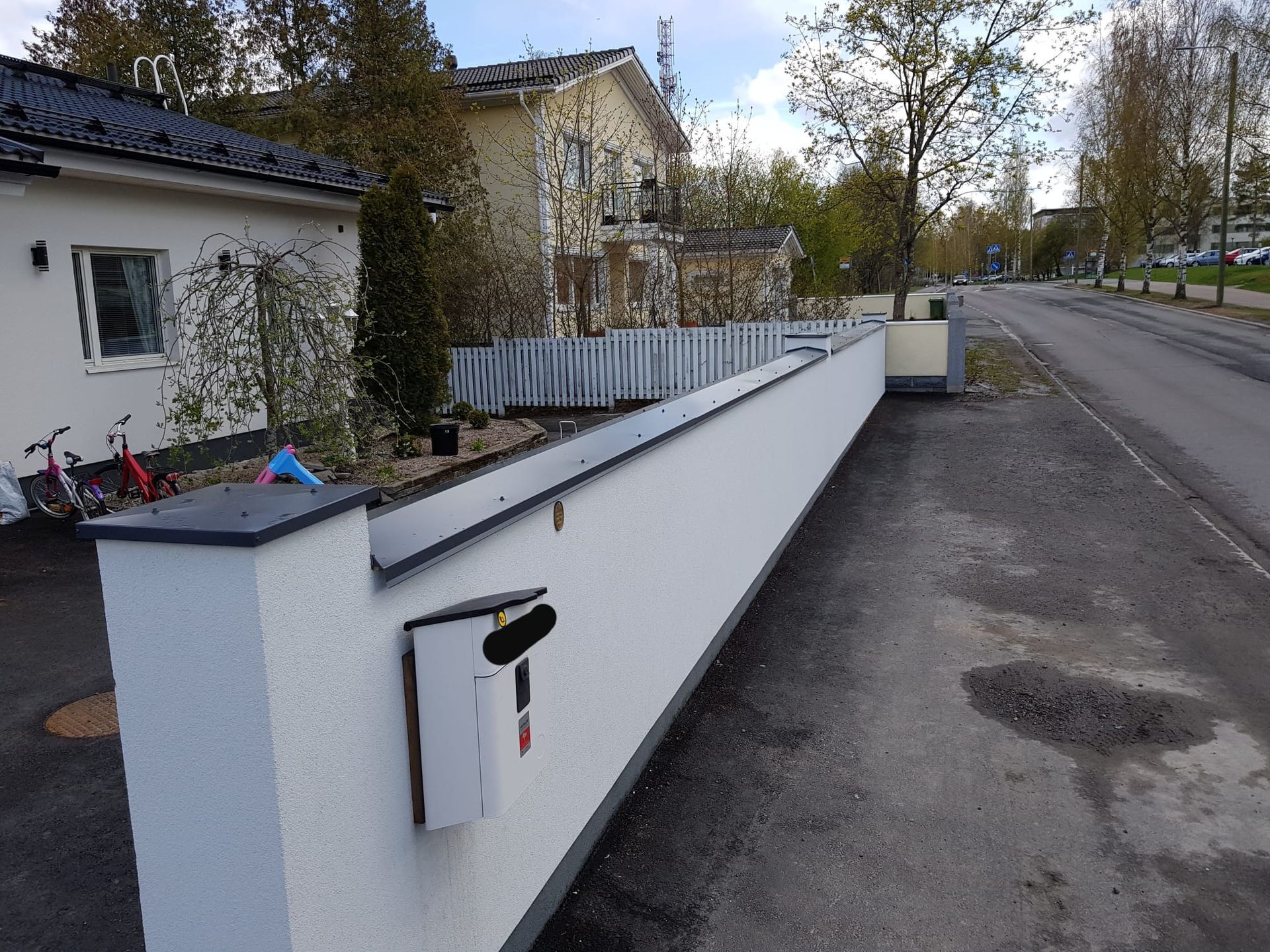 Valkoisen kivimuurin tyylikäs suojapellitys ja pihapiirin viimeistely Pirkanmaalla.