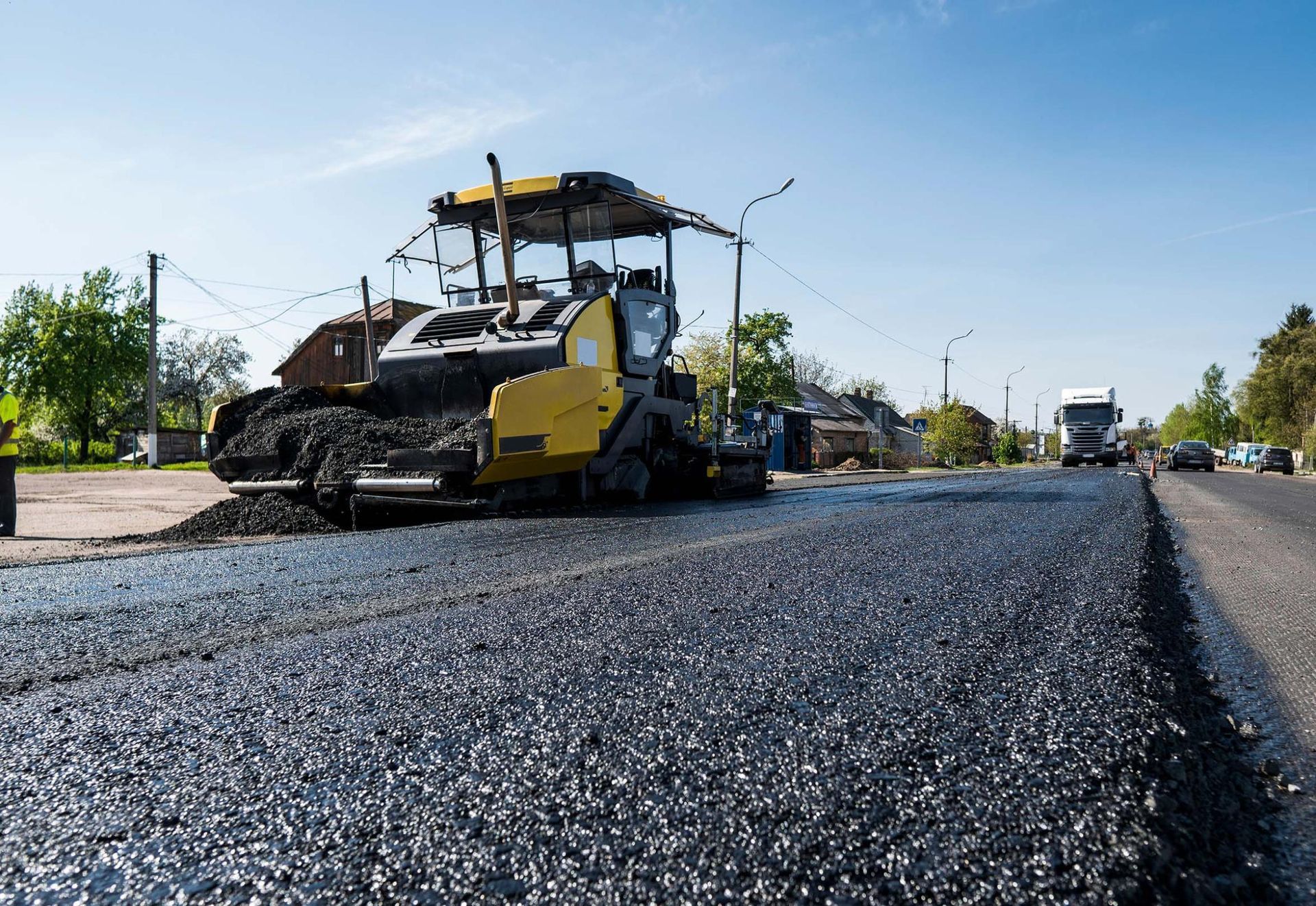 Finisseuse étalant de l’asphalte frais sur une chaussée sous un ciel bleu dégagé
