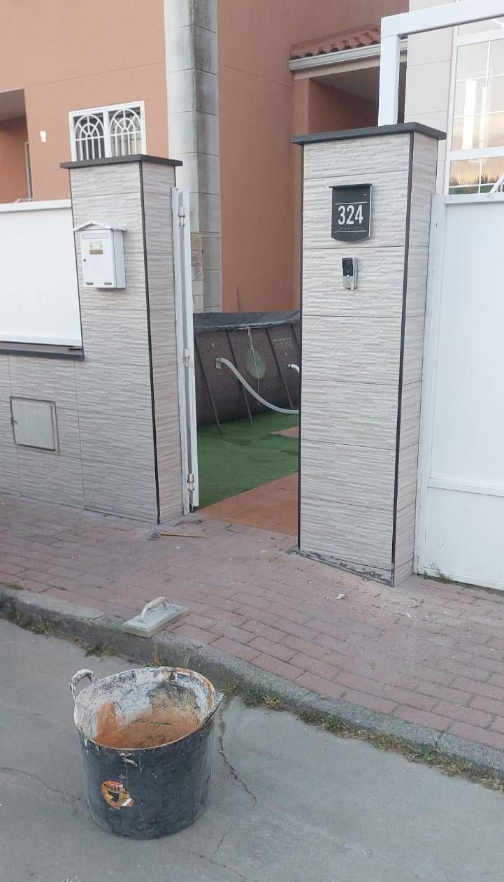 Un cubo negro se encuentra frente a la entrada de una puerta con la dirección 134; se ve césped verde.