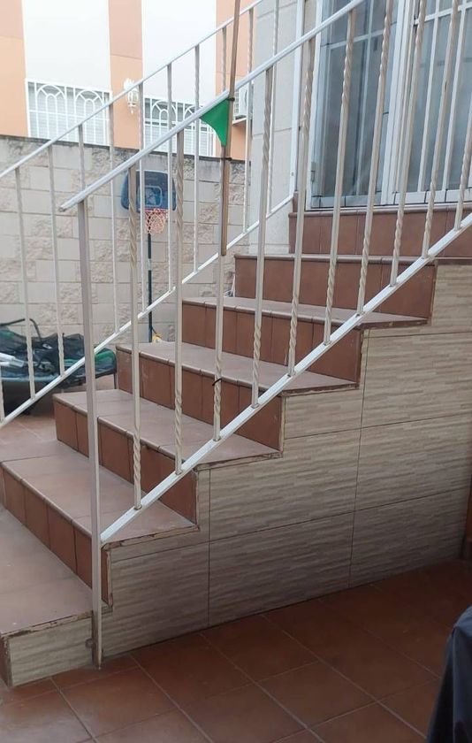 Una ventana blanca está abierta y ofrece una vista de un edificio.