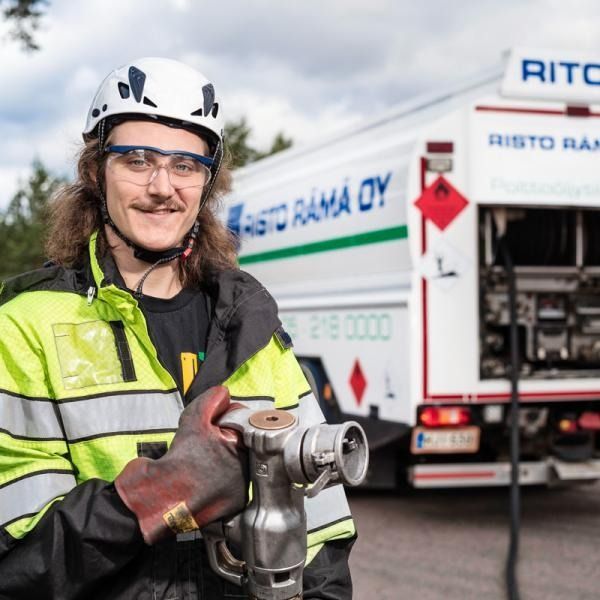 Huomiovaatteisiin pukeutunut työntekijä pitelee metallityökalua Risto Ratina Oy:n huoltoauton edessä.
