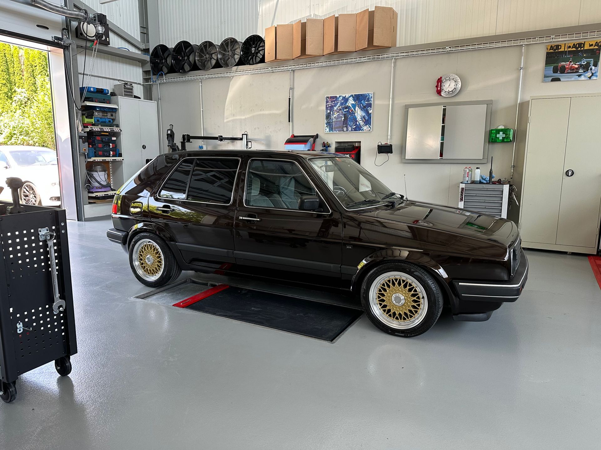 Black classic car parked in a garage with gold rims.