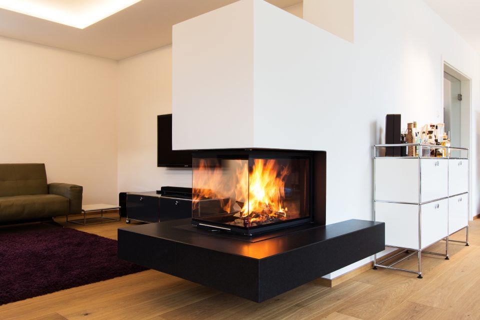 Modernes Wohnzimmer mit schwarz-weißem Kamin, knisterndem Feuer und minimalistischen Möbeln