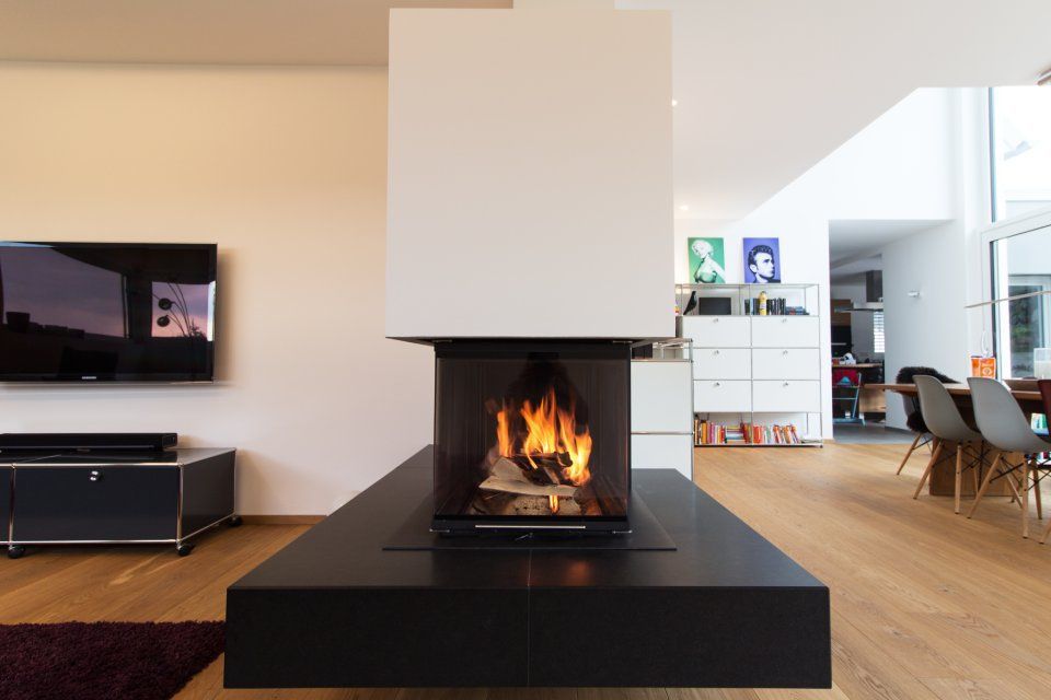 Modernes Wohnzimmer mit einem zentralen schwarzen Kamin und einem an der Wand montierten Fernseher auf der linken Seite.