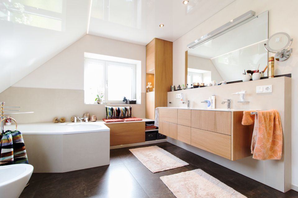 Helles, modernes Badezimmer mit Doppelwaschbecken, freistehender Badewanne und orangefarbenen Handtuchakzenten