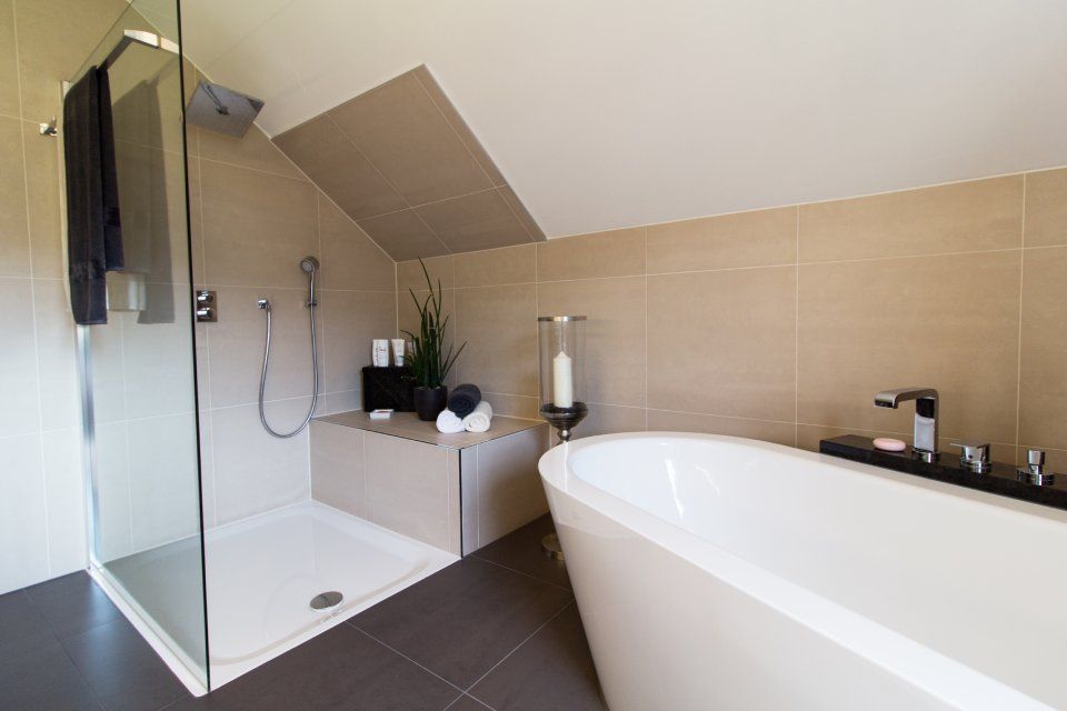 Modernes Badezimmer mit Glasdusche, freistehender Badewanne, beigefarbenen Fliesen und dunklen Bodenfliesen