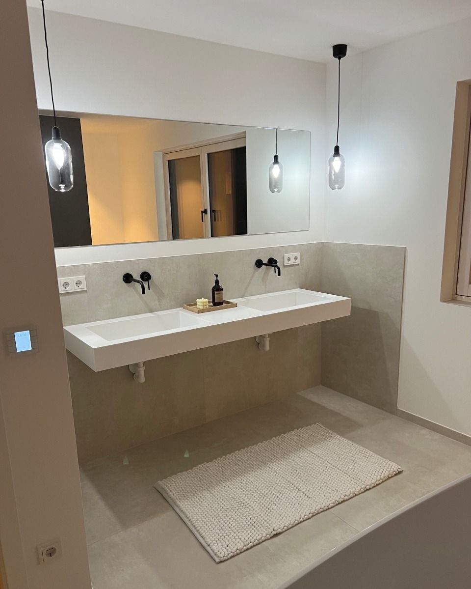 Modernes Badezimmer mit freischwebendem Doppelwaschbecken, Spiegel, Pendelleuchten und beigefarbenem Teppich