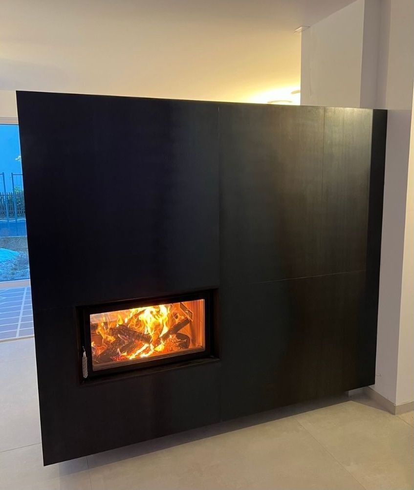 Schwarzer, an der Wand montierter Kamin mit sichtbaren Flammen in einem modernen Innenraum
