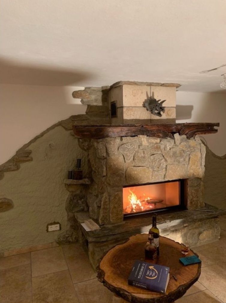 Steinkamin mit brennendem Feuer im Wohnzimmer, davor ein dekorativer Kaminsims und ein Couchtisch.