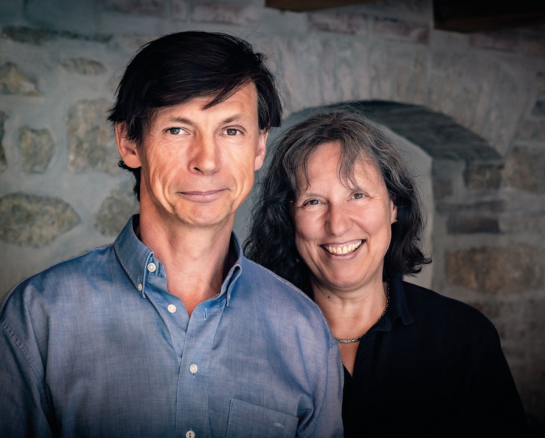 Ein Mann und eine Frau stehen nebeneinander und lächeln in die Kamera.