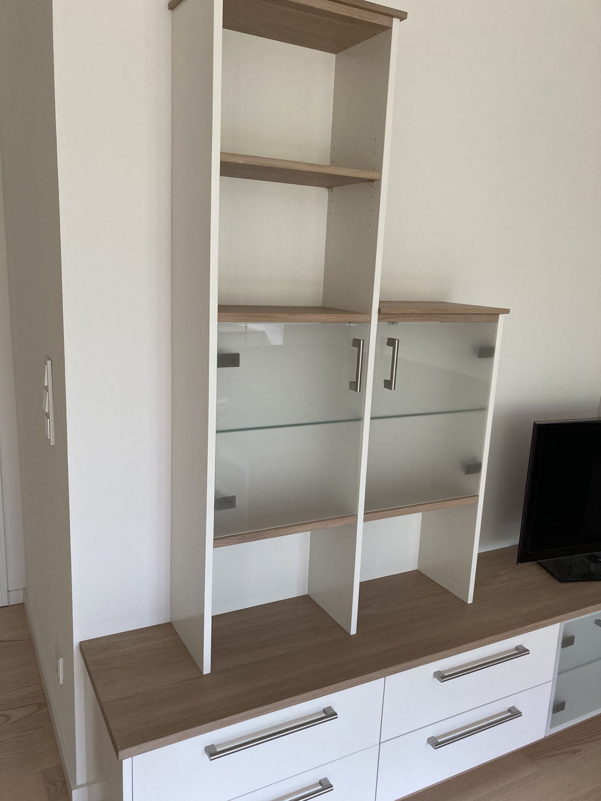 Weiße Wohnwand mit Holzakzenten und Milchglastüren