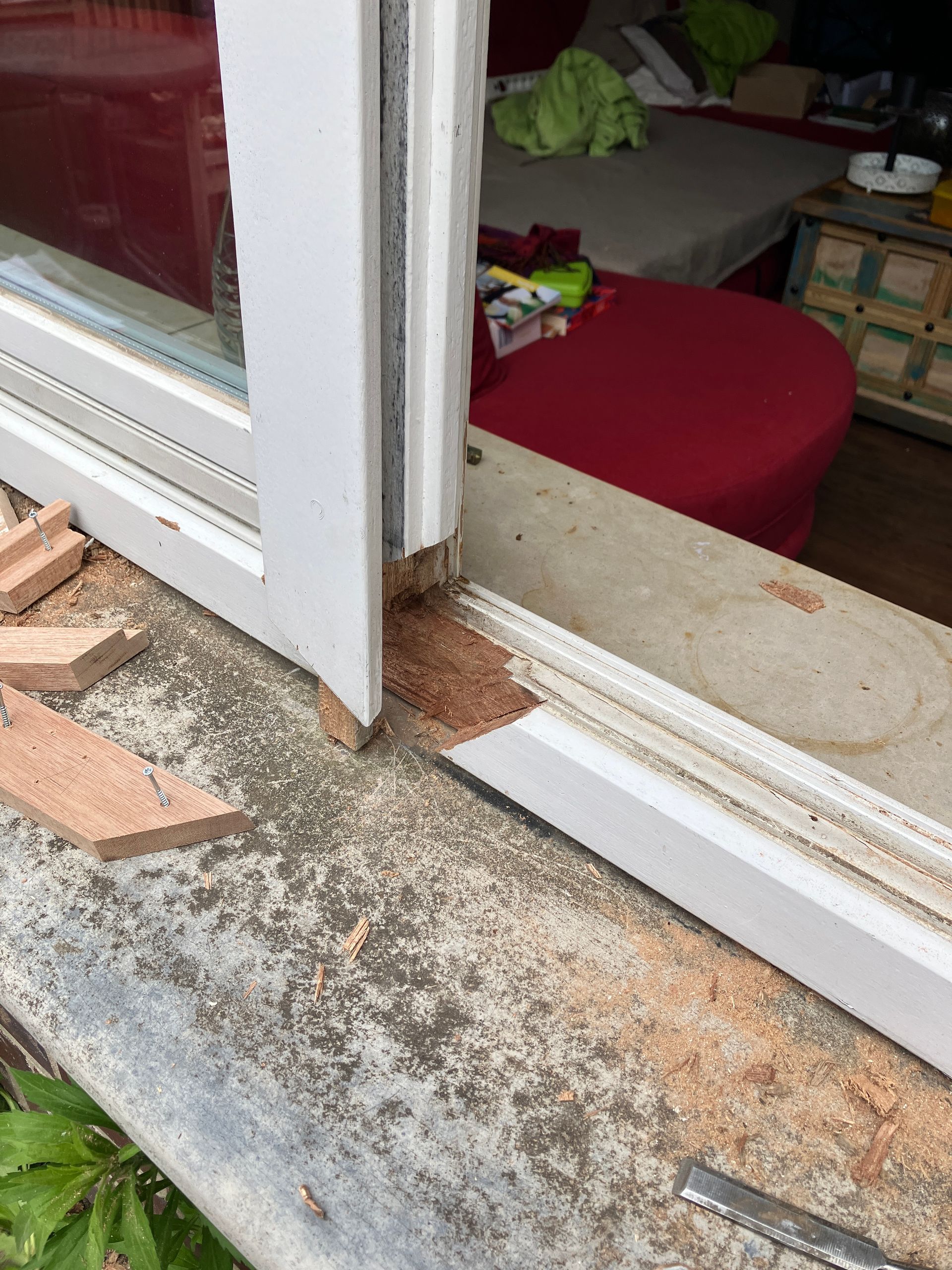 Ausgestemmte schadhafte Stelle am Holzfensterrahmen und zugeschnittene Passstuecke aus Holz fuer die Reparatur