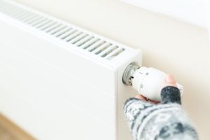 Una persona está ajustando un termostato en un radiador.