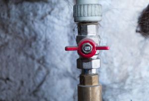 Un primer plano de una válvula roja en una tubería de agua.