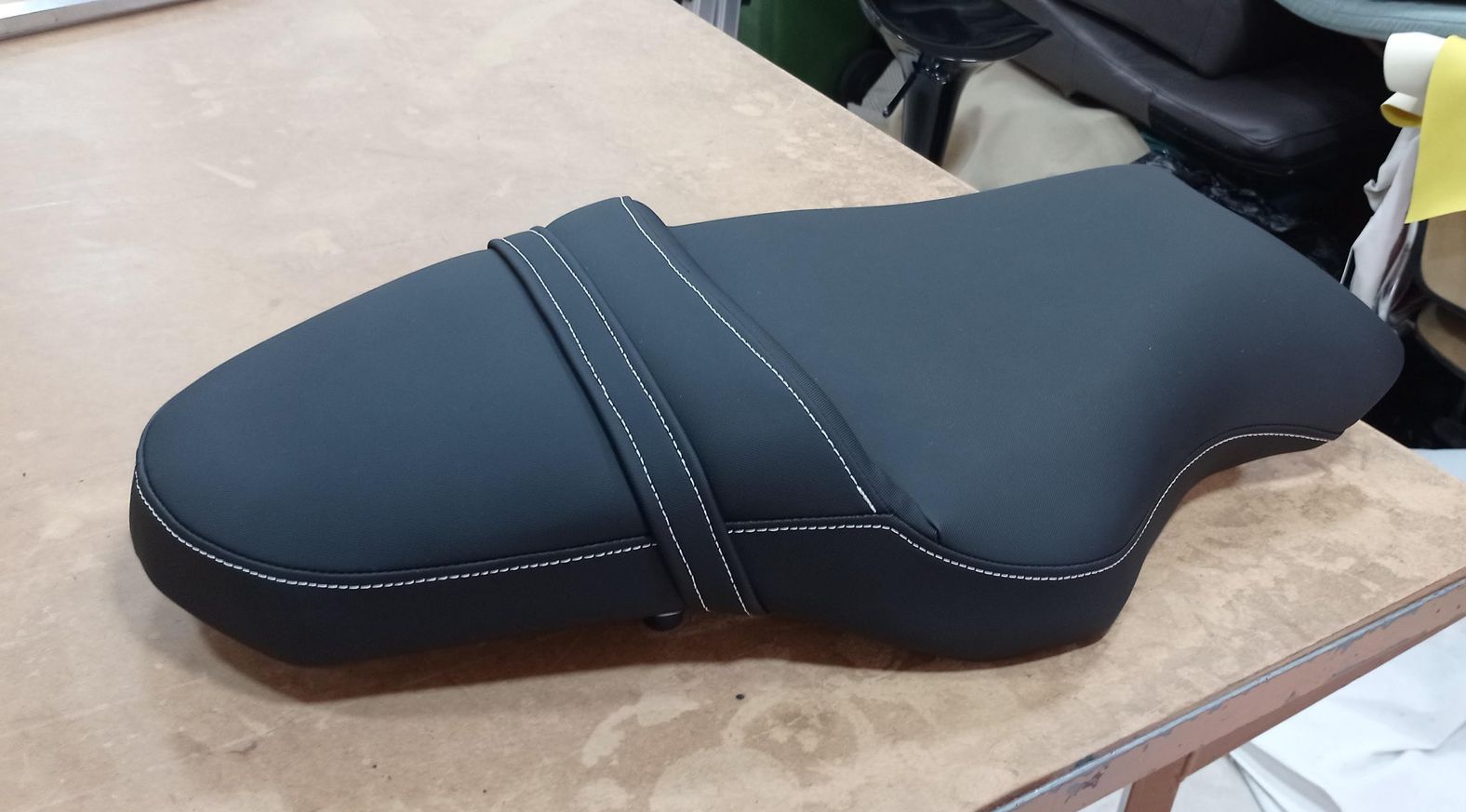 Un asiento de motocicleta negro está sobre una mesa de madera.