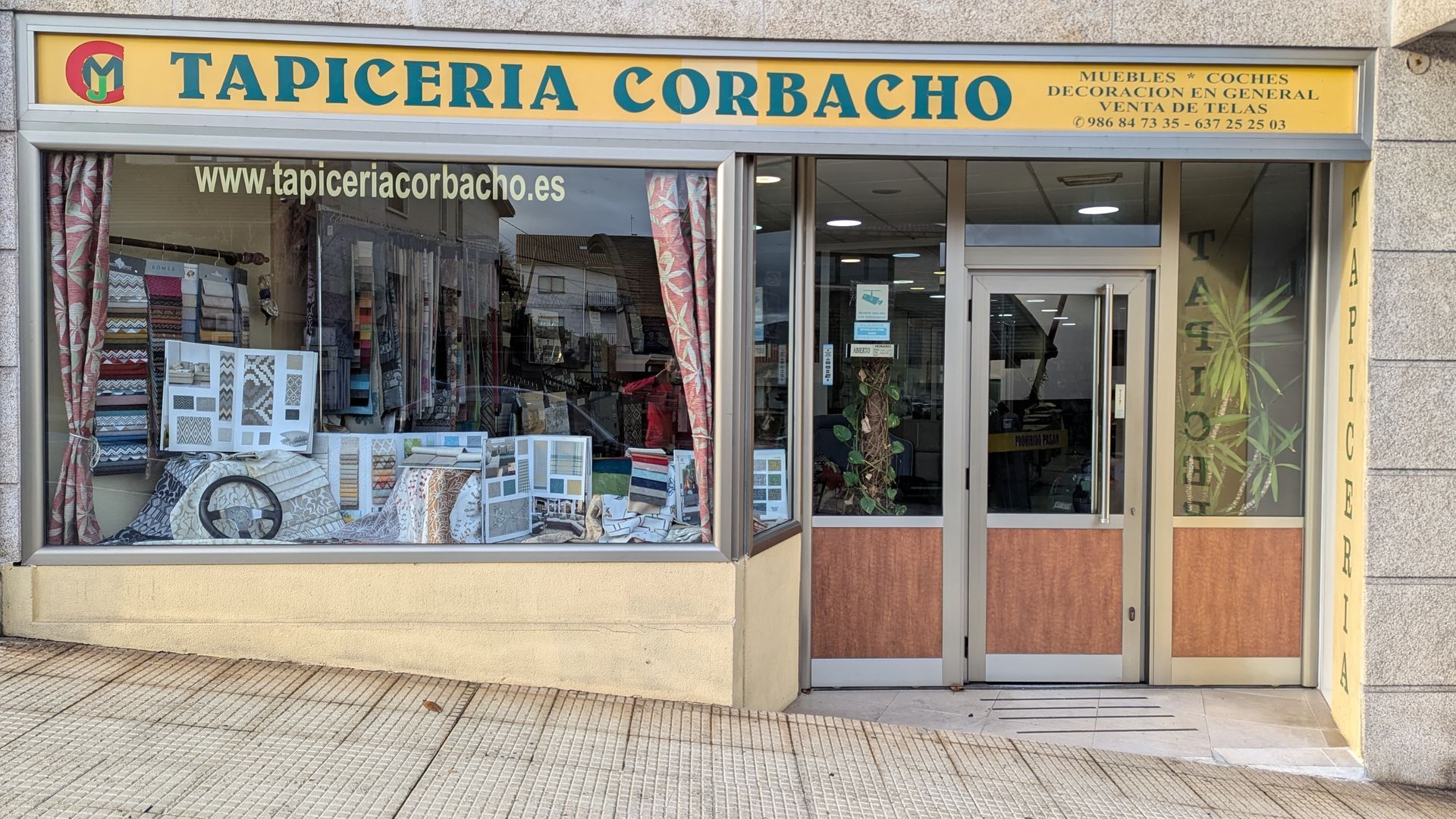 Un escaparate con un cartel amarillo que dice tapicería corbacho