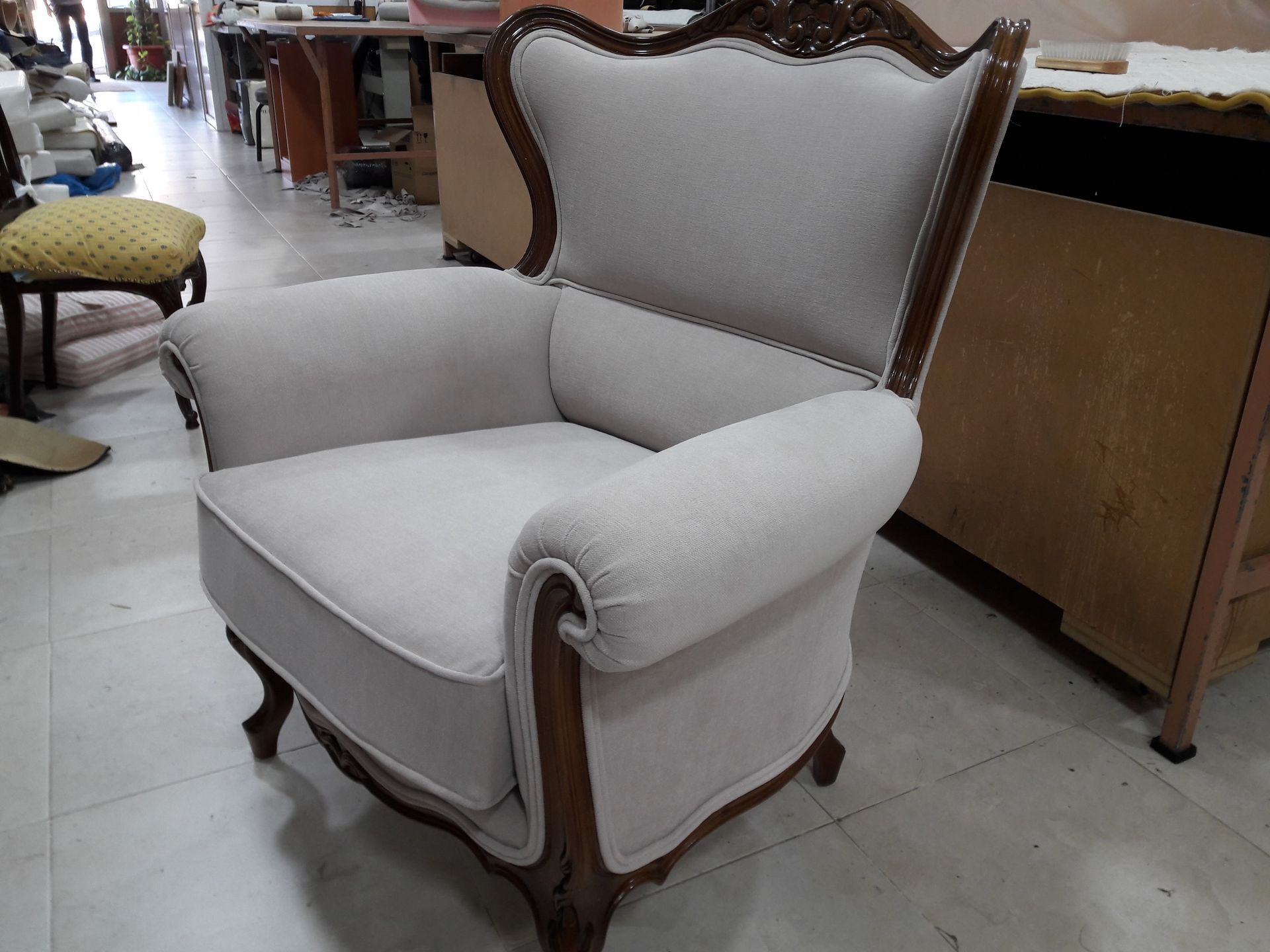 Una silla blanca con marco de madera está colocada sobre un suelo de baldosas.