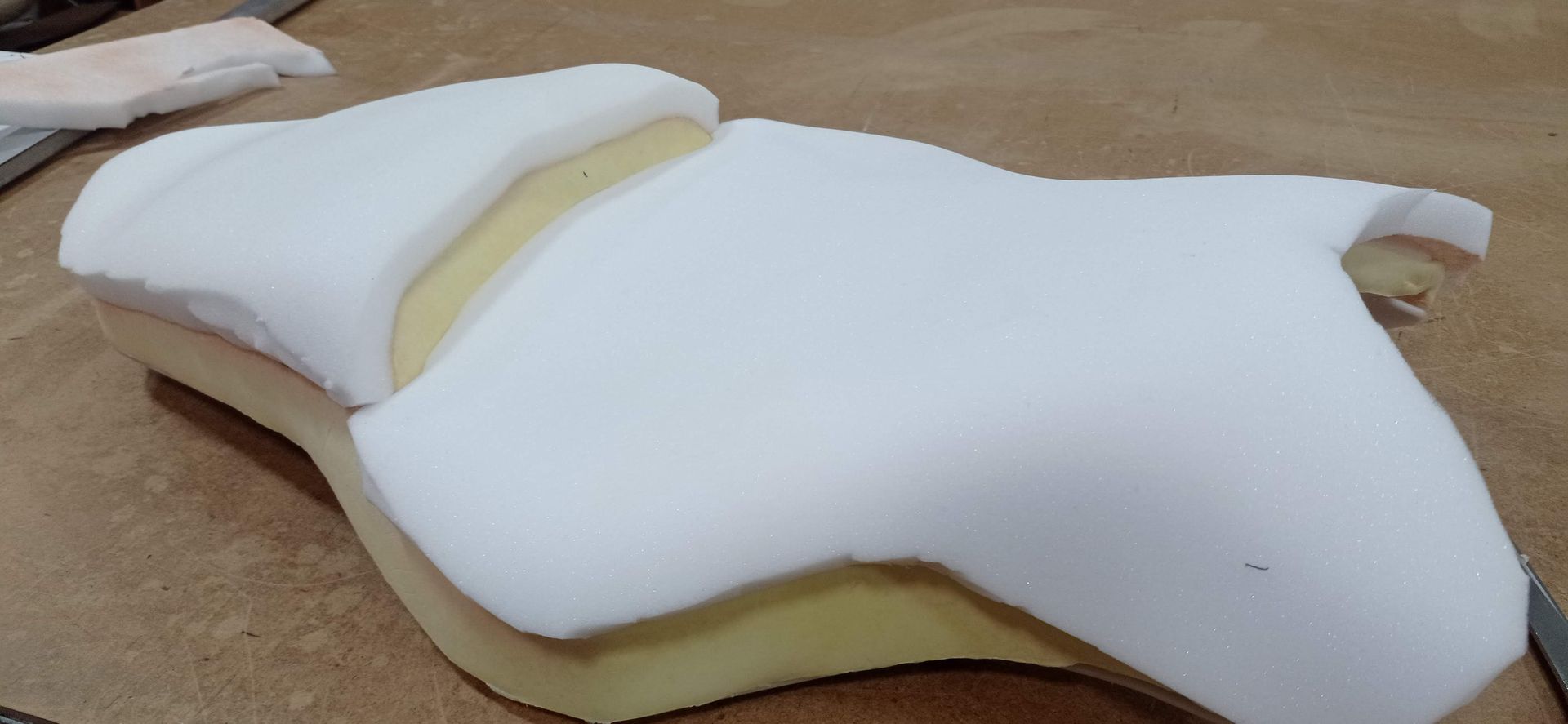 Un trozo de espuma blanca reposa sobre una mesa de madera.