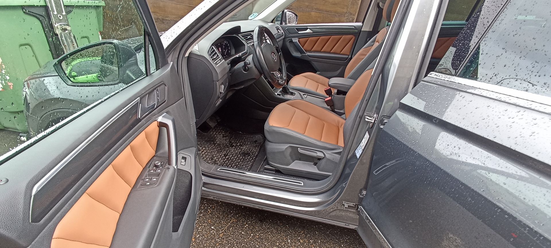 El interior de un coche con la puerta abierta y asientos marrones.