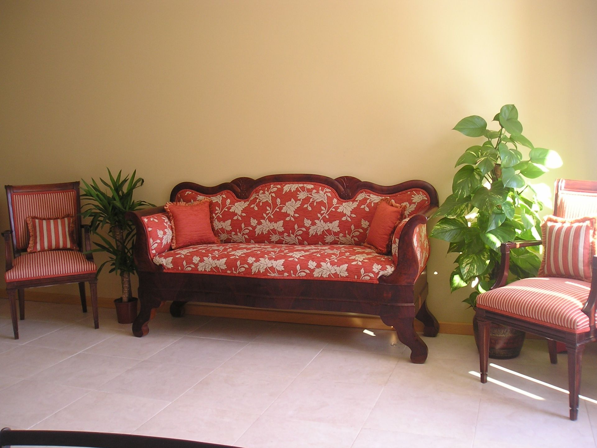 Una sala de estar con un sofá y sillas y una planta.