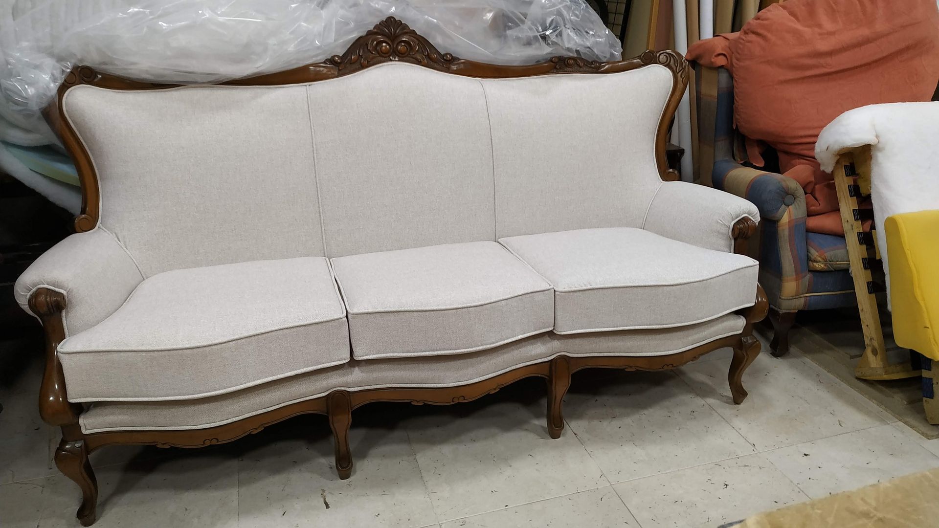 Un sofá blanco está sentado en una habitación al lado de una silla amarilla.