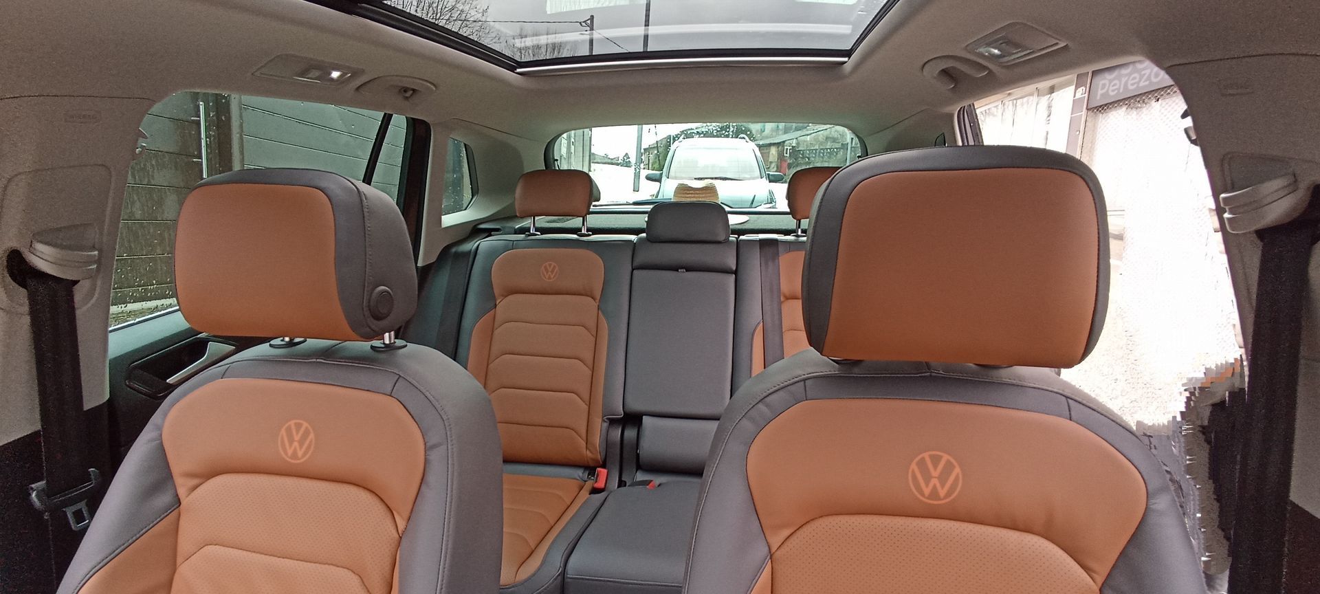 El interior de un Volkswagen con asientos marrones y grises y un techo corredizo.