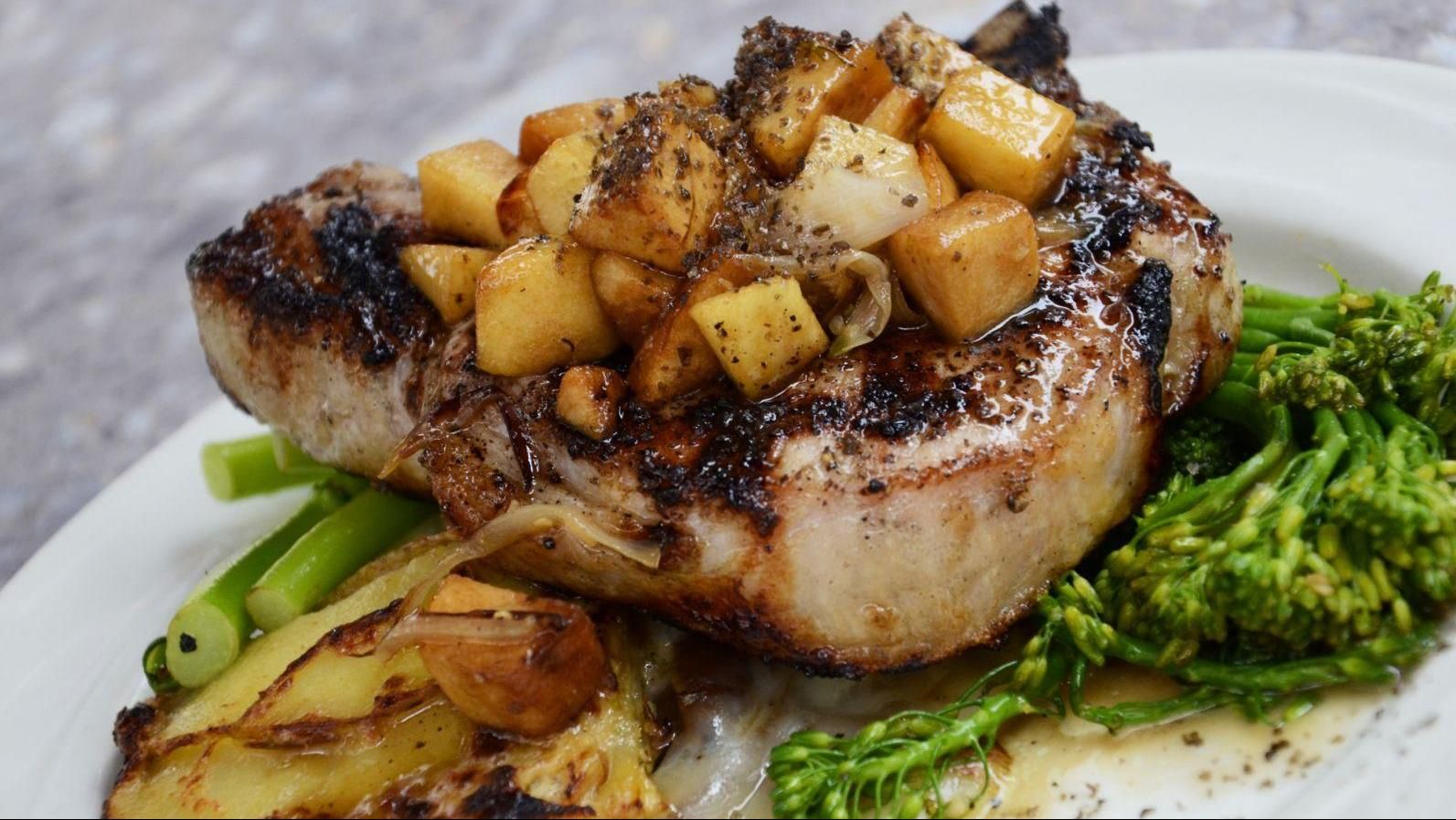 Een wit bord belegd met vlees, aardappelen en broccoli.