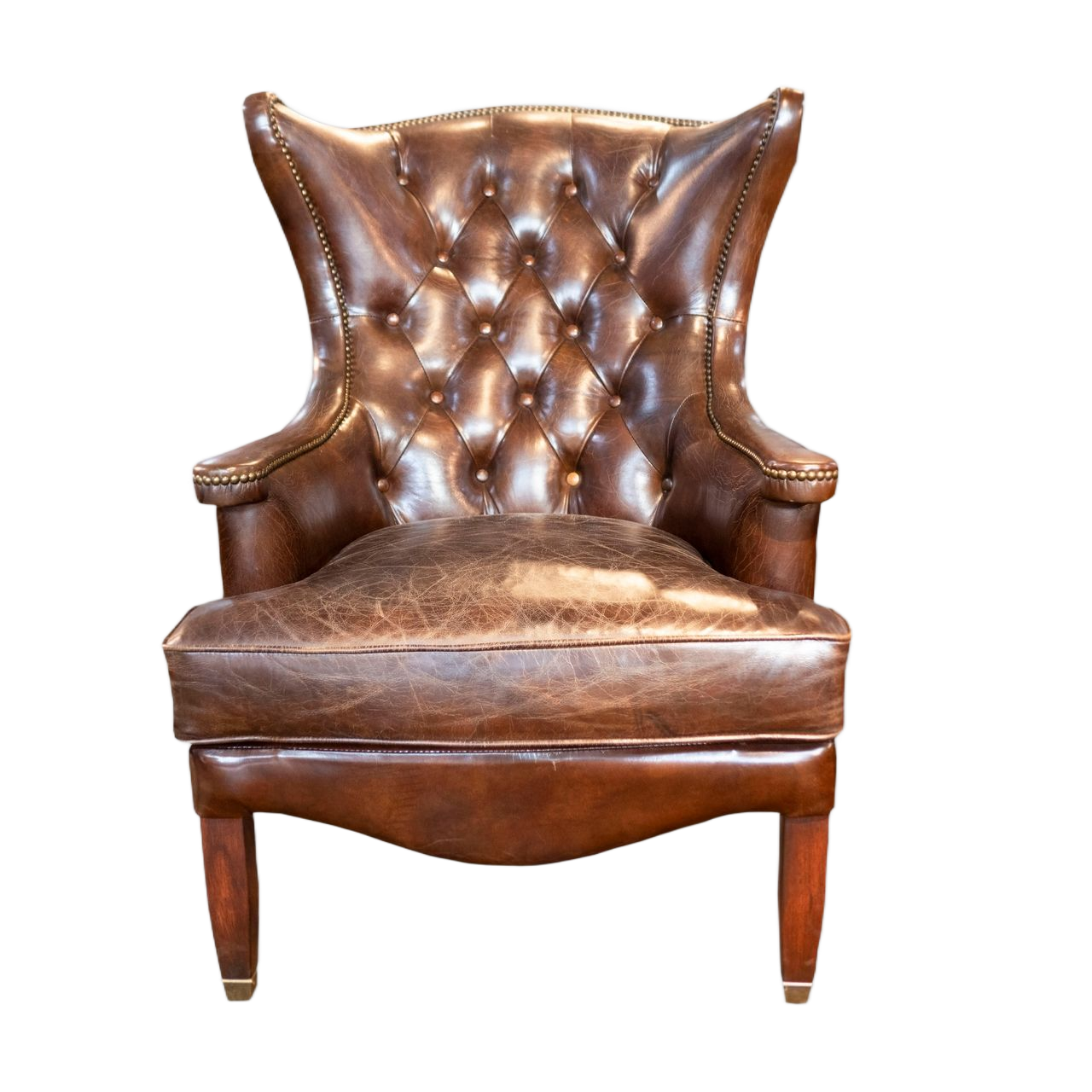 Fauteuil à oreilles capitonné en cuir marron avec pieds en bois, sur fond blanc.