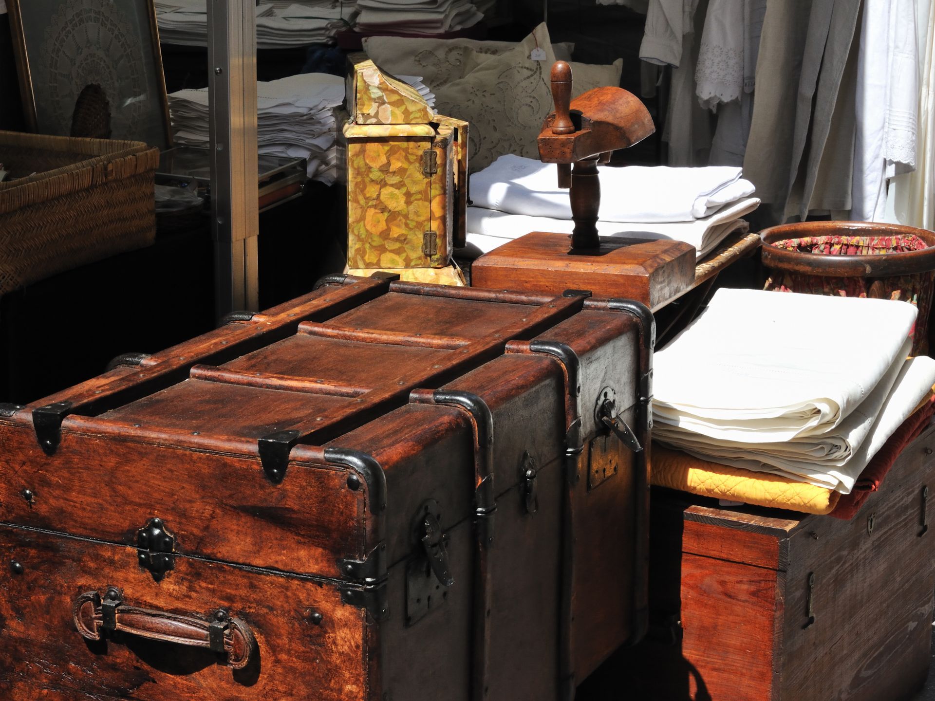 Des malles et des boîtes en bois anciennes sont exposées.