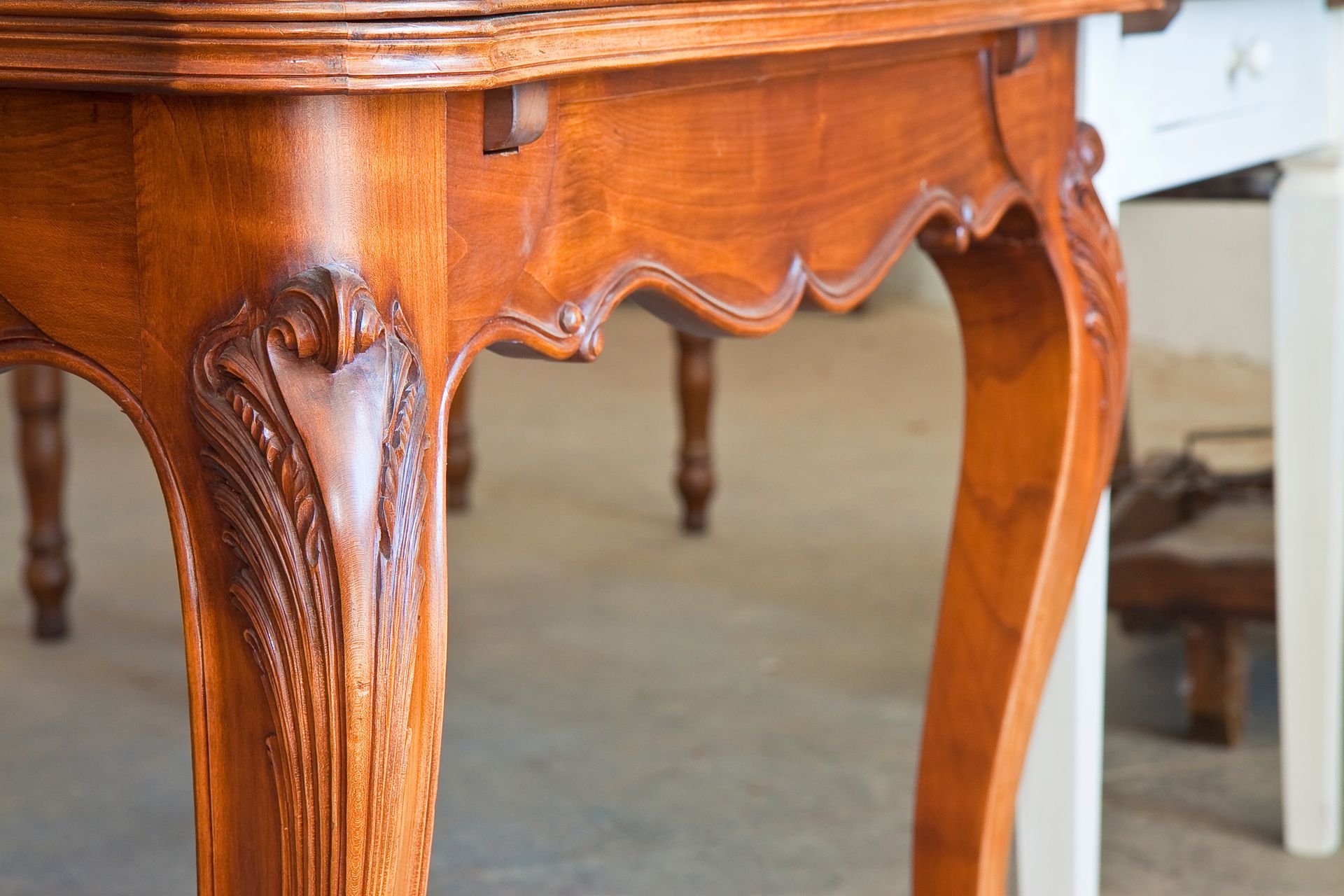 Gros plan sur un pied de table en bois richement teinté et orné de détails sculptés.