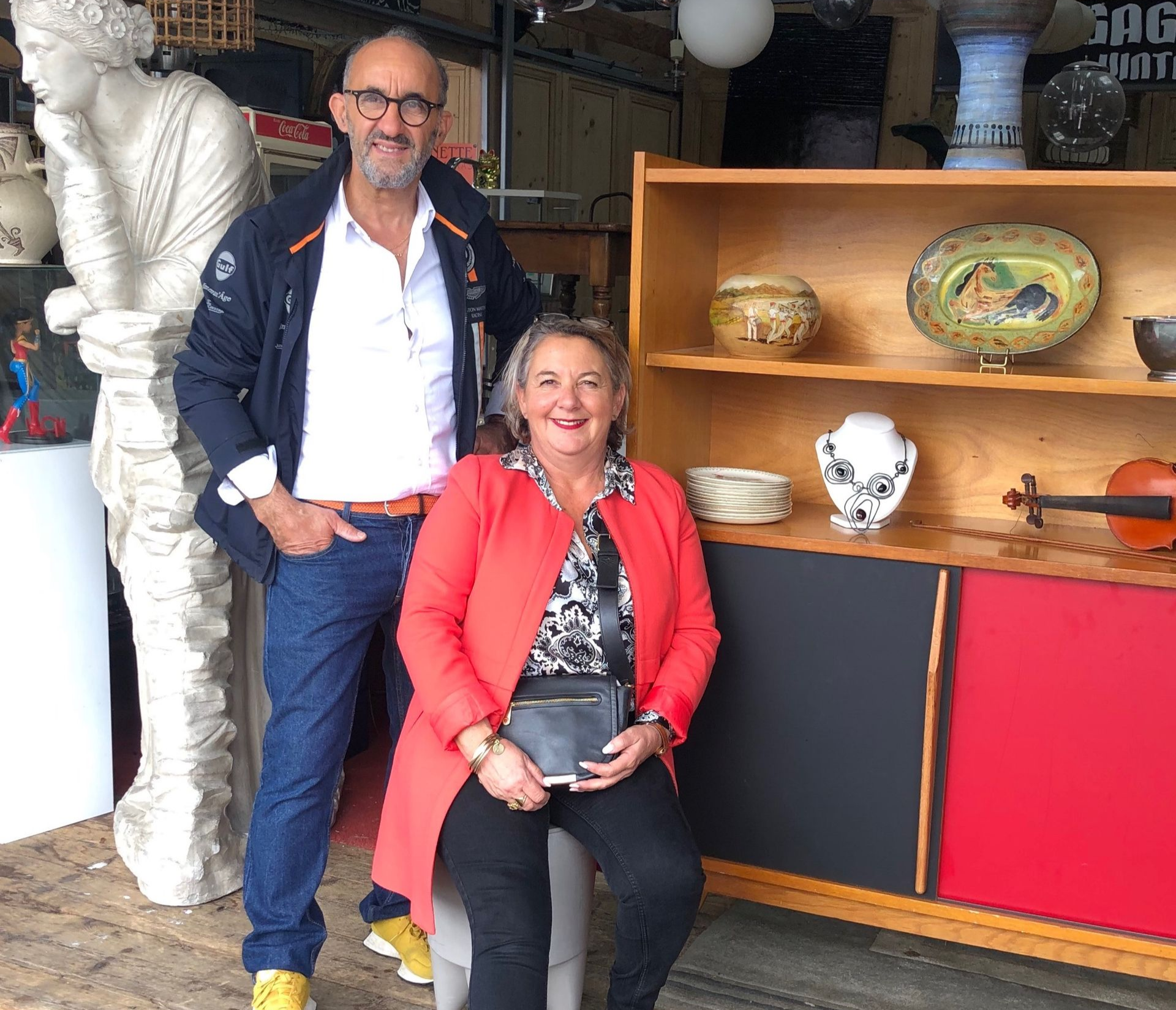 Un homme et une femme se tiennent près de meubles anciens. En extérieur.