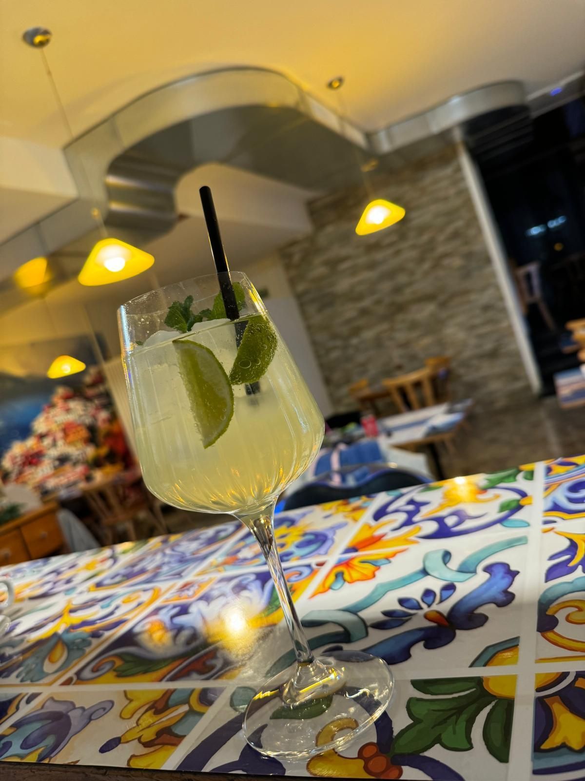 verre de cocktail avec un alcool jaune, des rondelles de citron et des feuilles de menthe.